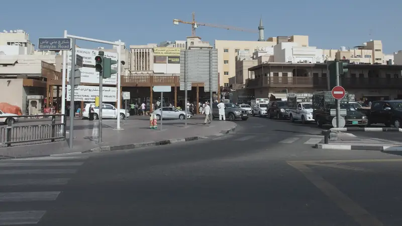 A street junction with traffic lights, low buildings and a minaret behind